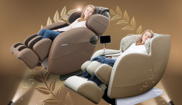 dios_6800_amazon_best_lm6800 - #1 USA Premier Full Body Massage Chair Two people reclining in beige Kahuna massage chairs in a gold-toned showroom with decorative leaf motifs in the background.